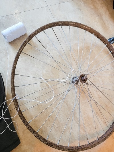 A bike wheel rim gets new life as a spider web on a Halloween Mantel