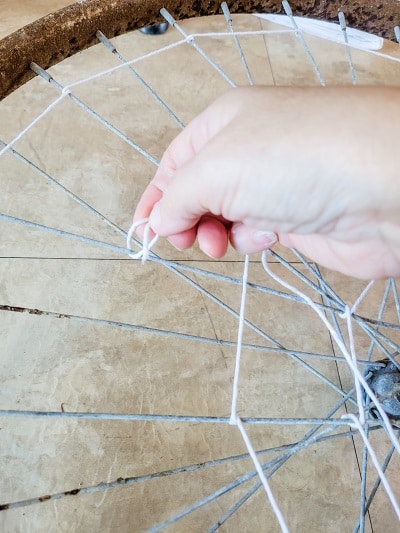 A bike wheel rim gets new life as a spider web on a Halloween Mantel