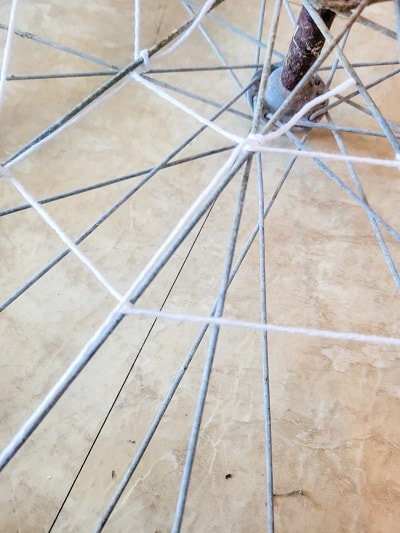 A bike wheel rim gets new life as a spider web on a Halloween Mantel