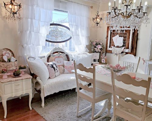A romantic shabby chic dining room with stained glass, chandelier and setee