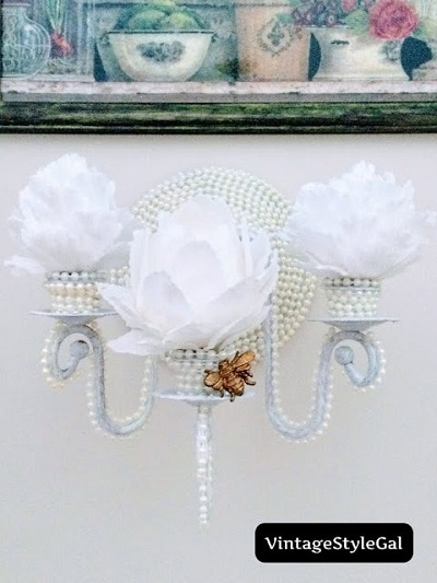 A white wall sconce covered in pearls
