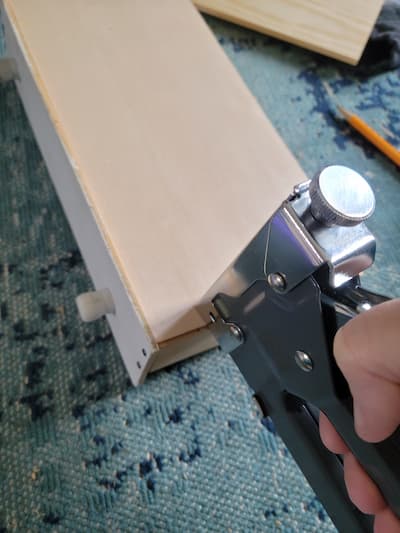 Using staple gun to attach balsam wood to bottom of drawer bottoms