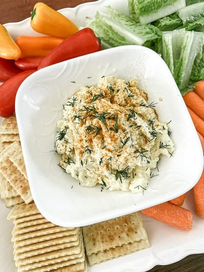 Dip in a white bowl surrounded by vegetables