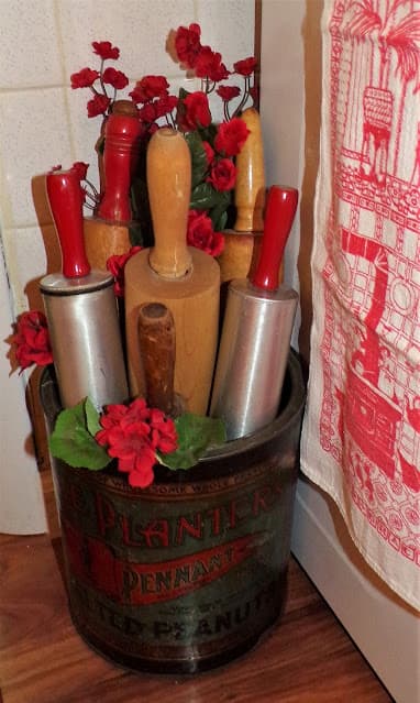 An old tin with red handled rolling pins