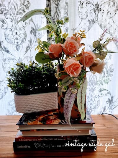 Pink Roses and green plant in white pot on book stack