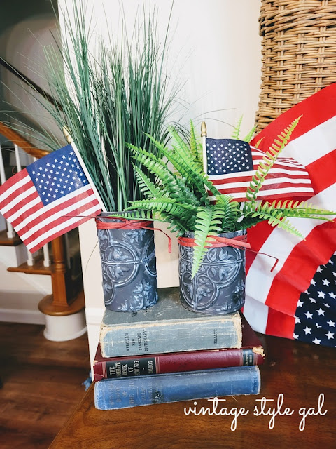 flags and greenery in tin panel vases on books