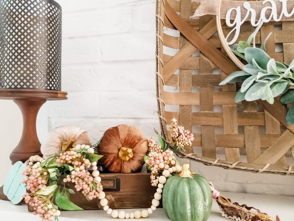 fall bead garland in vignette with tan and green pumpkins, berries and candlestick