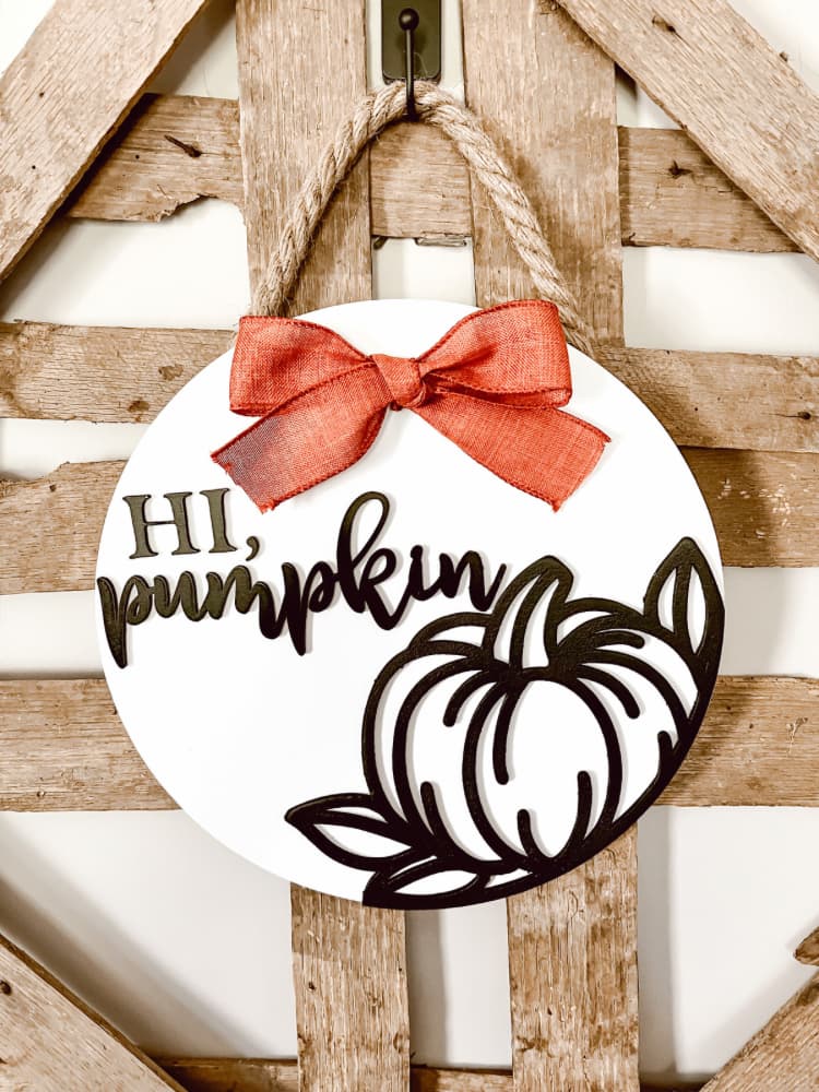 white wood circle sign with pumpkin outline and words hi pumpkin