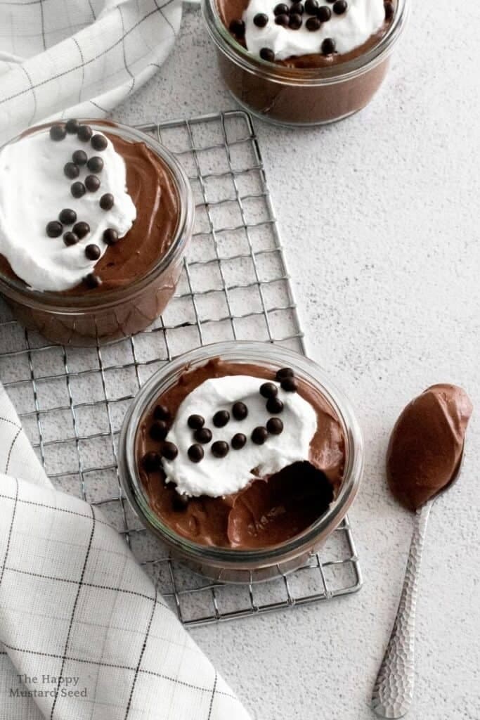 small jars of chocolate pudding with white cream on top