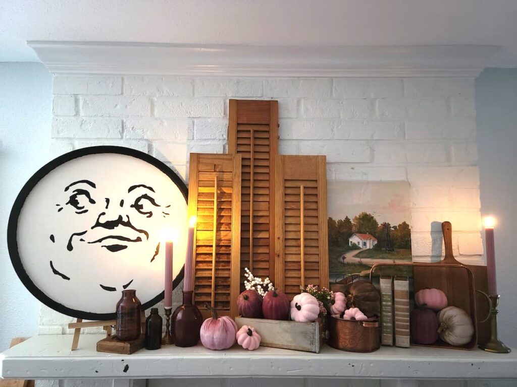 fall mantel with amber bottles, pink pumpkins and man in the moon