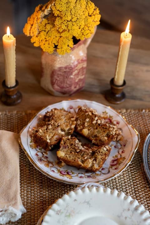 pieces of apple cake on plate with candles and flowers