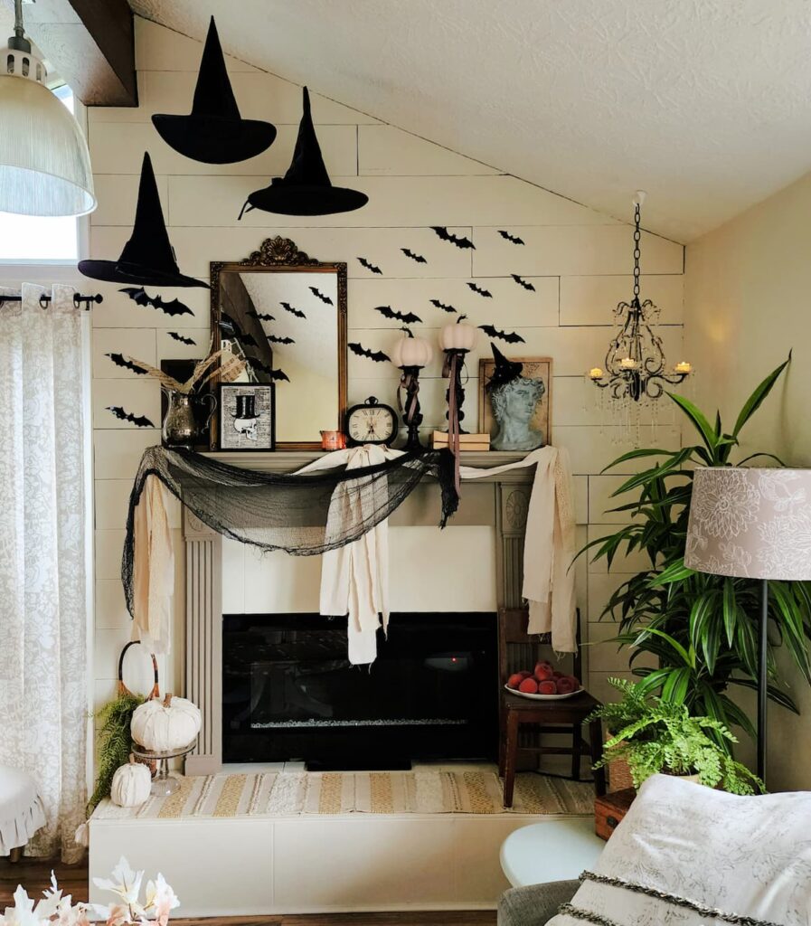 Mantel on white wall with hanging witch hats, paper bats, and decor