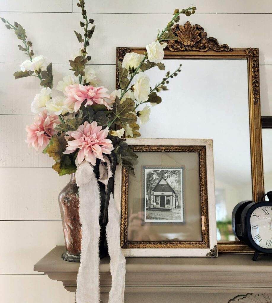 shelf with mirror, frame and amber jar of flowers