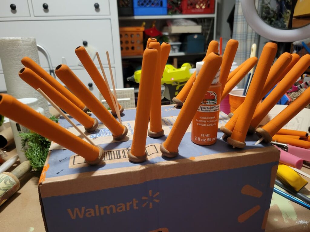 painting wood carrots on a box with skewers
