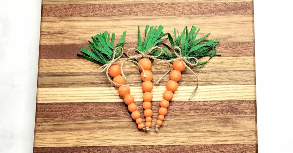 3 wood bead carrots on wood background