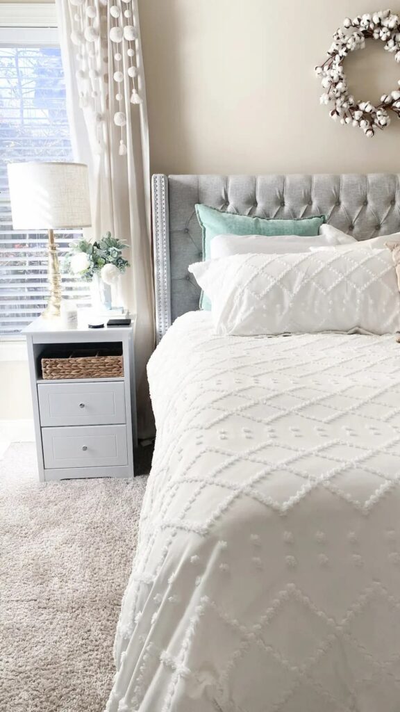 bed with white bedding and grey nightstand