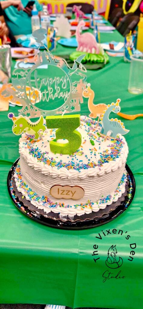 white cake with acrylic dinosaur topper
