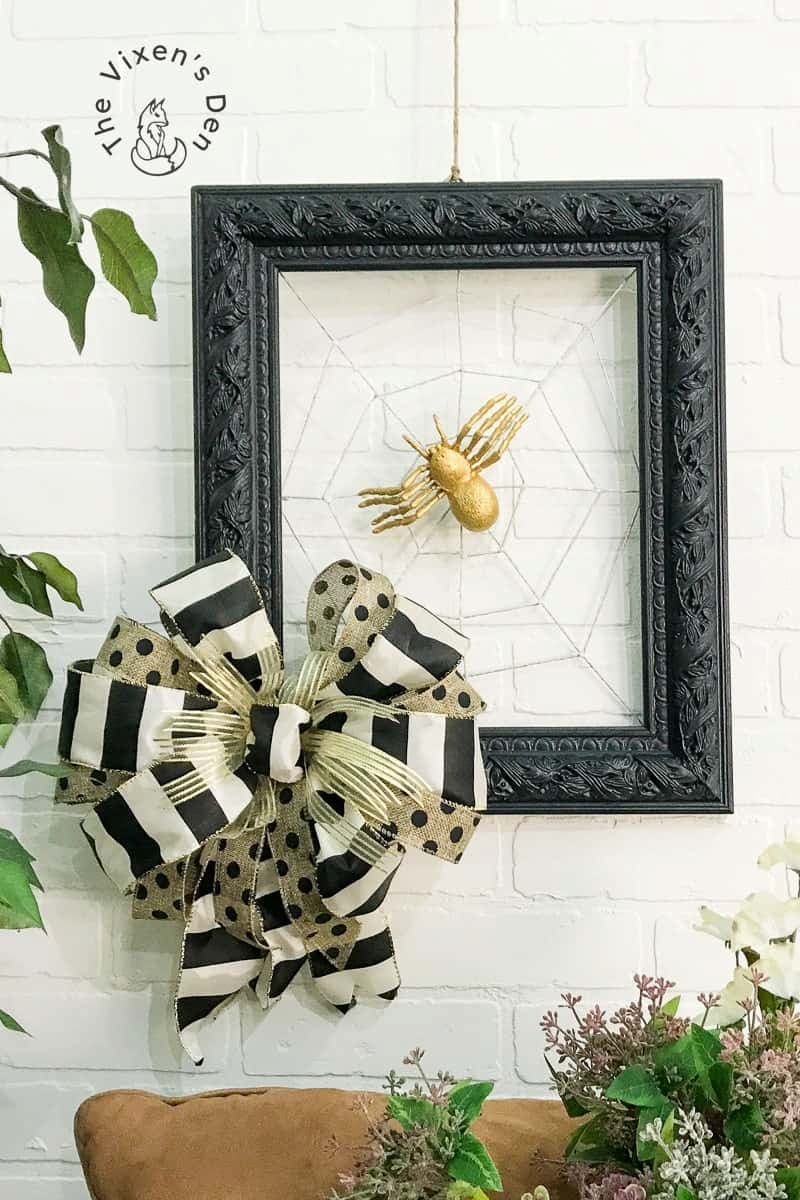 black frame on white wall with gold spider