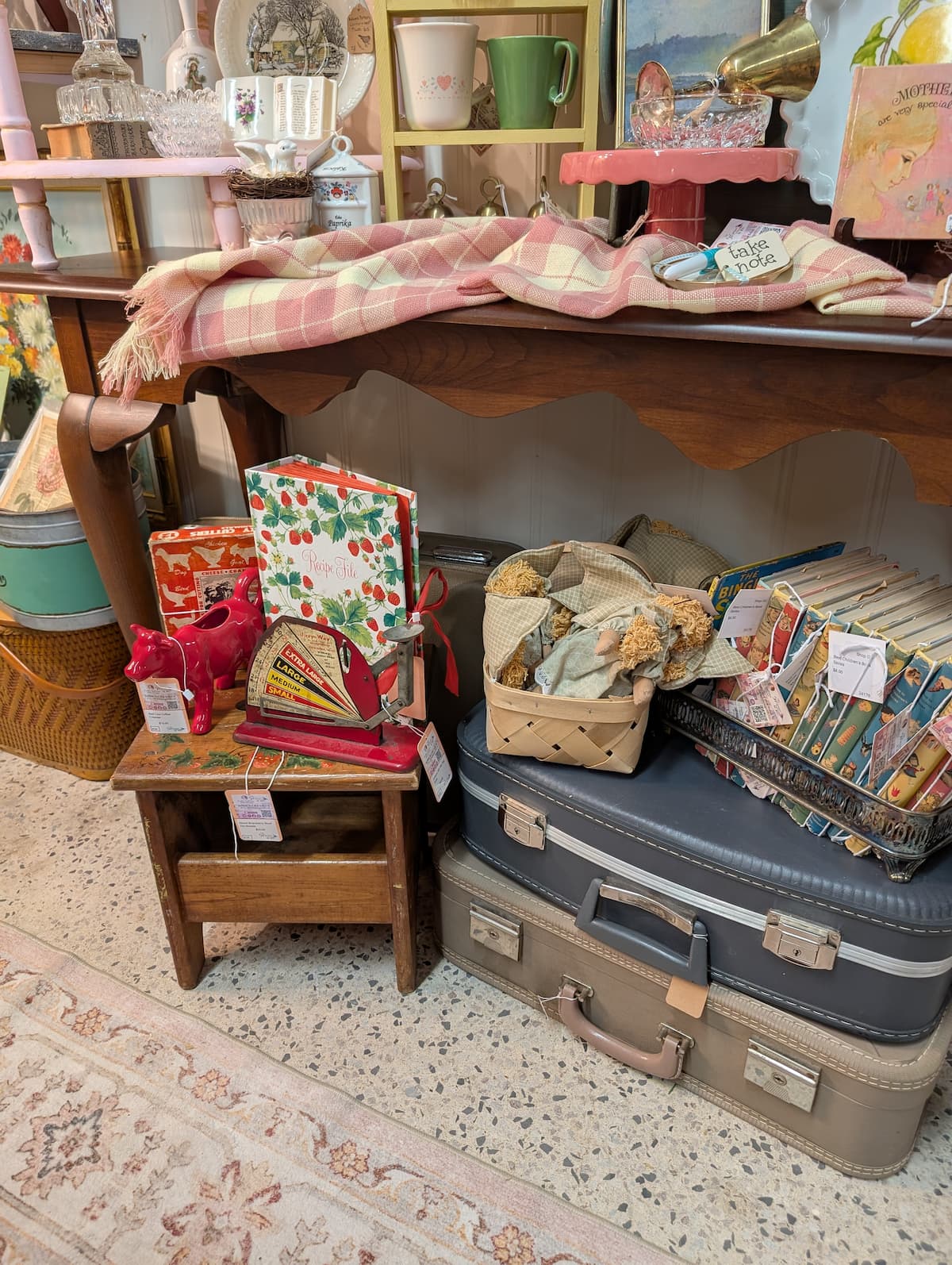 vignette in vintage booth with suitcases, bench, and books