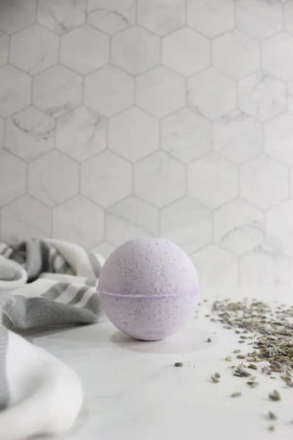 a lavender bath bomb on white surface